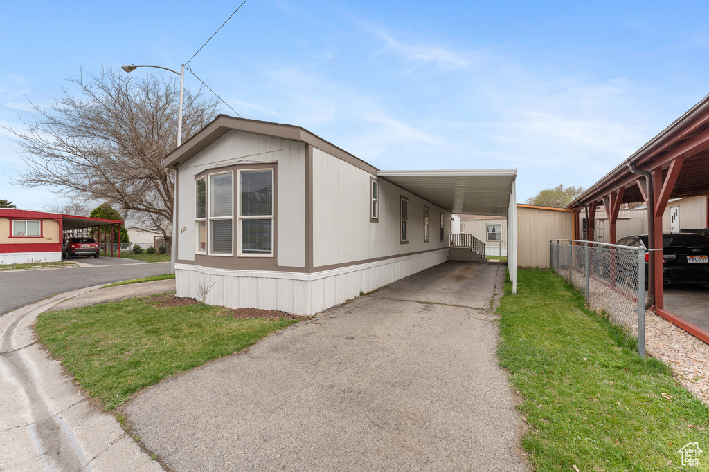 View of property exterior featuring aphalt driveway, a carport, and fence