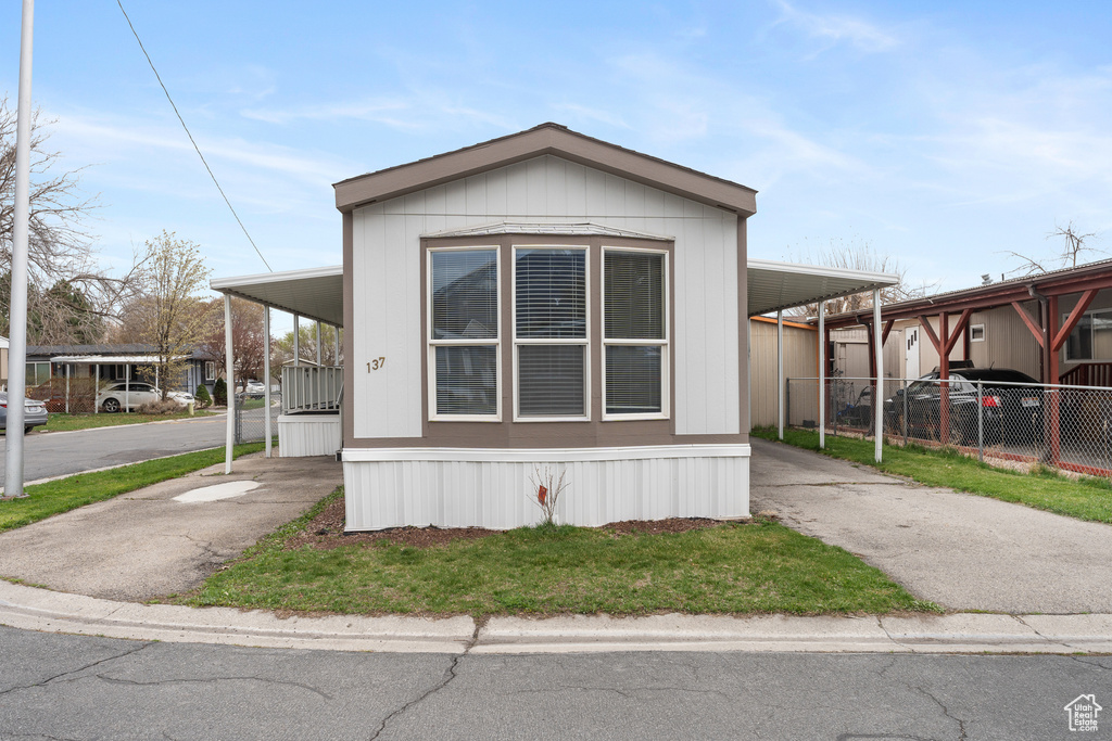 Manufactured / mobile home with a carport, fence, and driveway