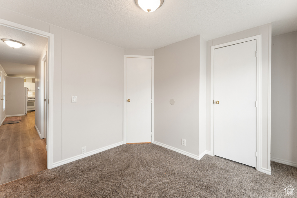 Unfurnished bedroom with a textured ceiling, baseboards, and carpet