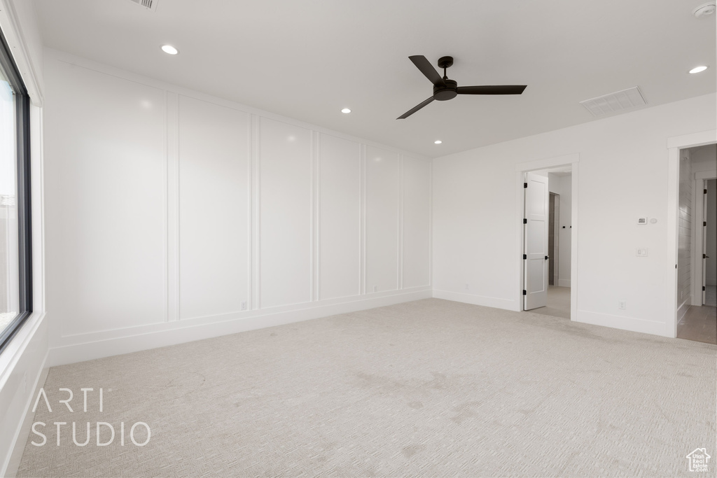 Empty room with ceiling fan, light colored carpet, a decorative wall, and recessed lighting