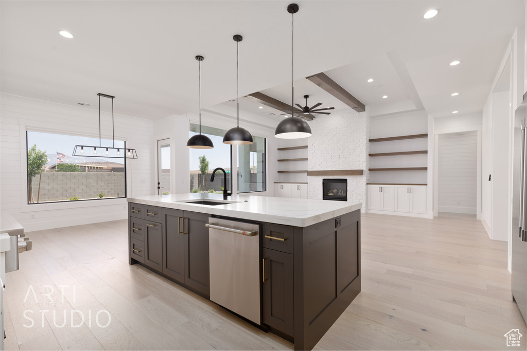 Kitchen with dishwasher, a sink, light wood-style flooring, a stone fireplace, and recessed lighting