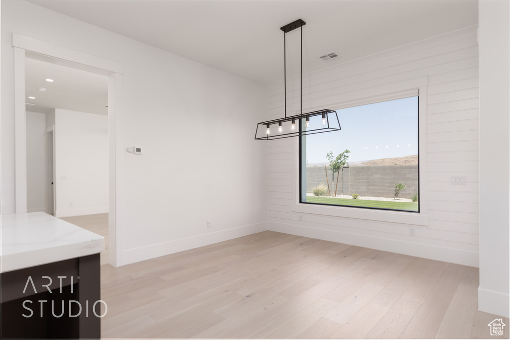 Unfurnished dining area featuring light wood-style floors, a chandelier, baseboards, and recessed lighting