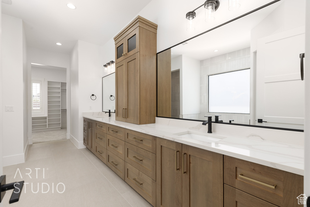 Full bath with double vanity, recessed lighting, baseboards, a spacious closet, and tile patterned flooring
