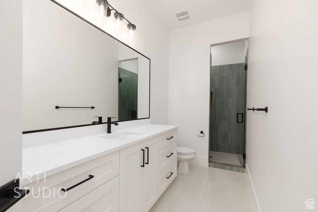 Bathroom featuring tile patterned floors, toilet, a stall shower, vanity, and baseboards