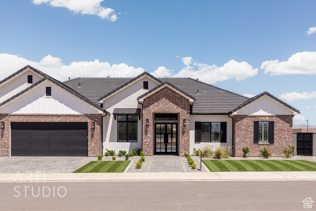 View of front facade with french doors, brick siding, and an attached garage