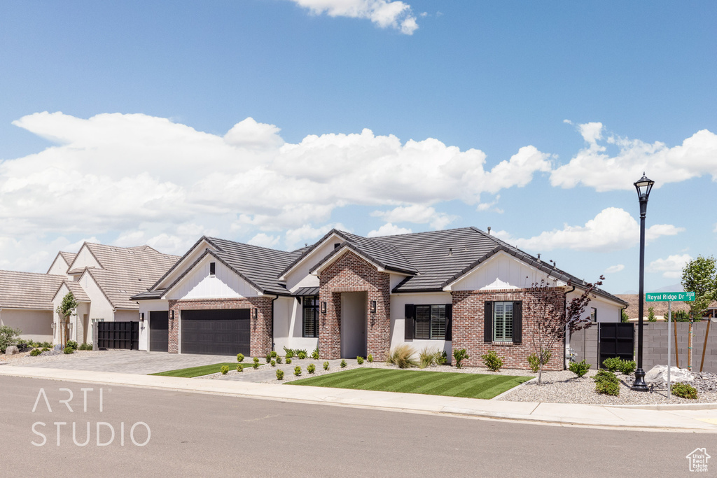 View of front of home featuring brick siding, an attached garage, concrete driveway, and a tile roof