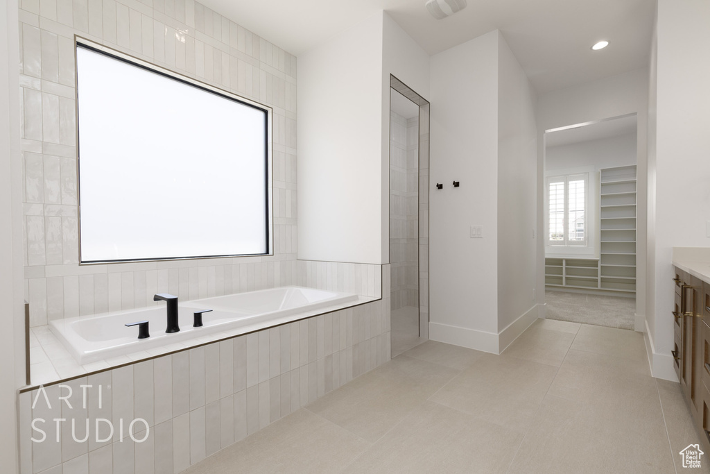 Full bathroom featuring a garden tub, vanity, tile patterned flooring, and baseboards