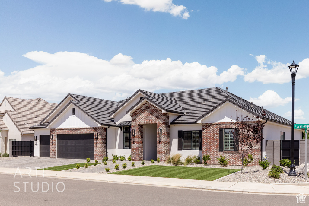 View of front of property featuring brick siding, a garage, a tiled roof, and driveway