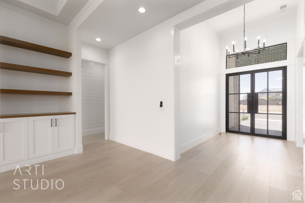 Empty room featuring a chandelier, light wood-style floors, french doors, recessed lighting, and baseboards