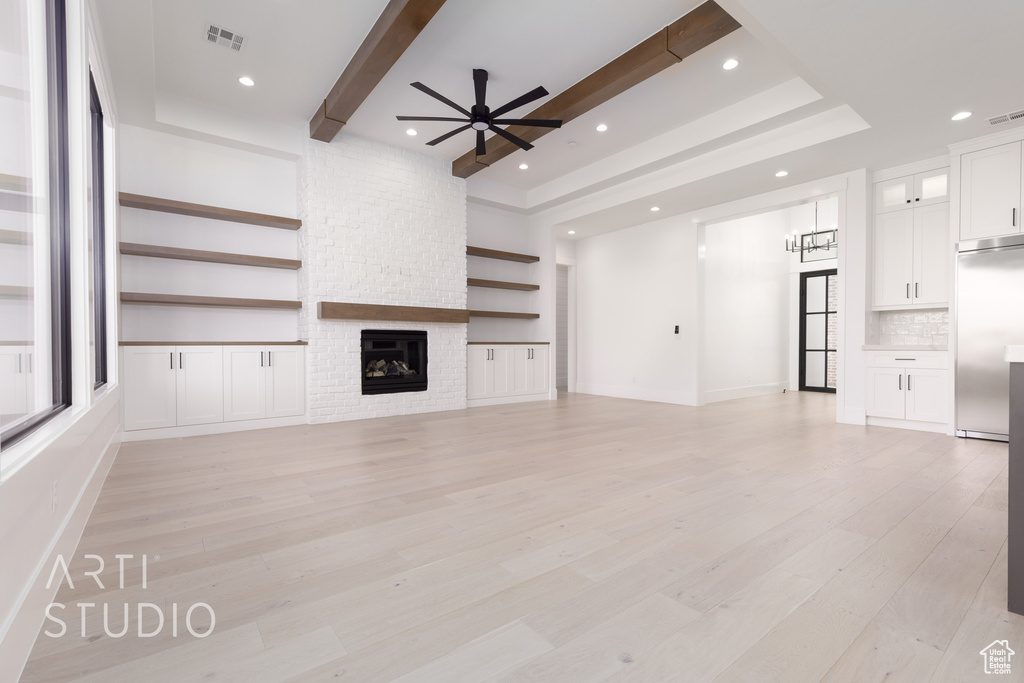 Unfurnished living room featuring a ceiling fan, light wood-style flooring, a fireplace, beamed ceiling, and recessed lighting
