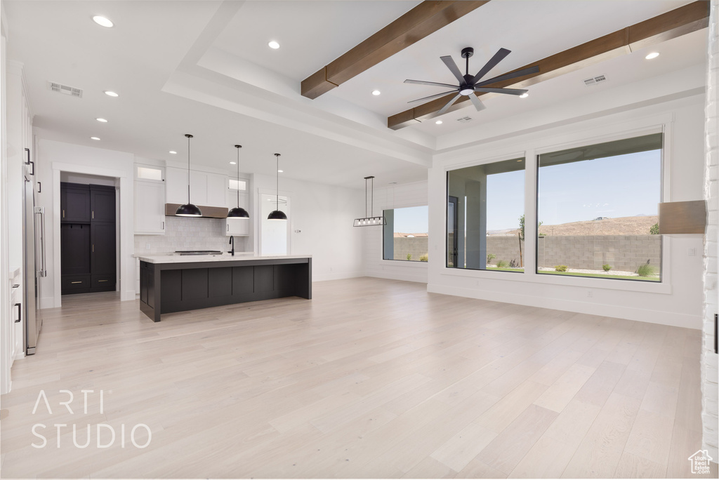 Unfurnished living room featuring light wood finished floors, a ceiling fan, recessed lighting, and beamed ceiling