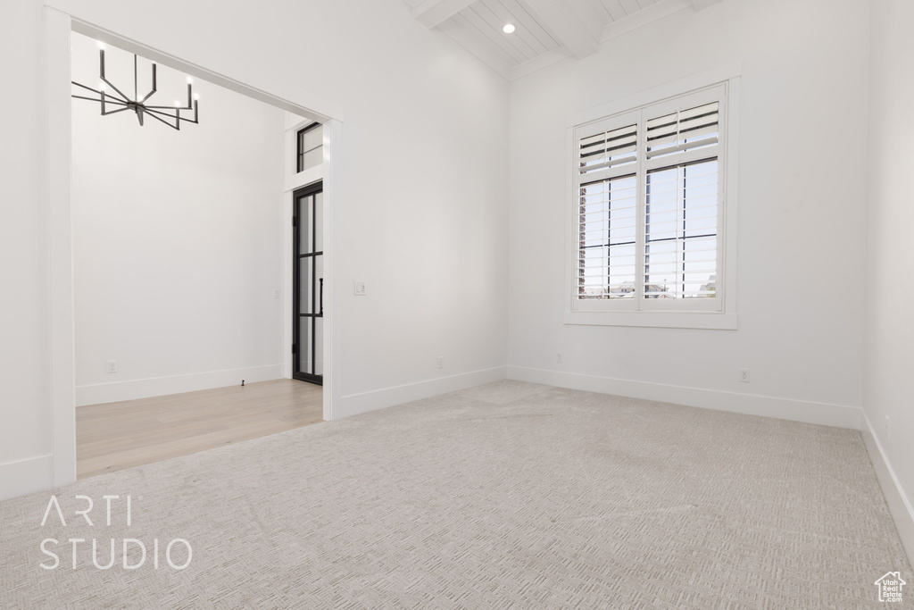Empty room with a chandelier, carpet flooring, beam ceiling, baseboards, and recessed lighting