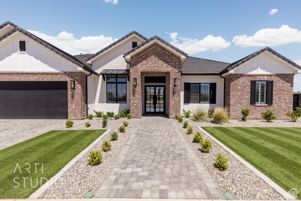 View of front of home with french doors, board and batten siding, brick siding, and a front lawn