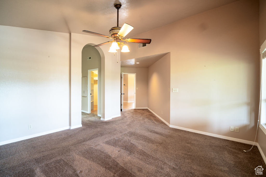 Spare room with carpet, ceiling fan, arched walkways, and baseboards