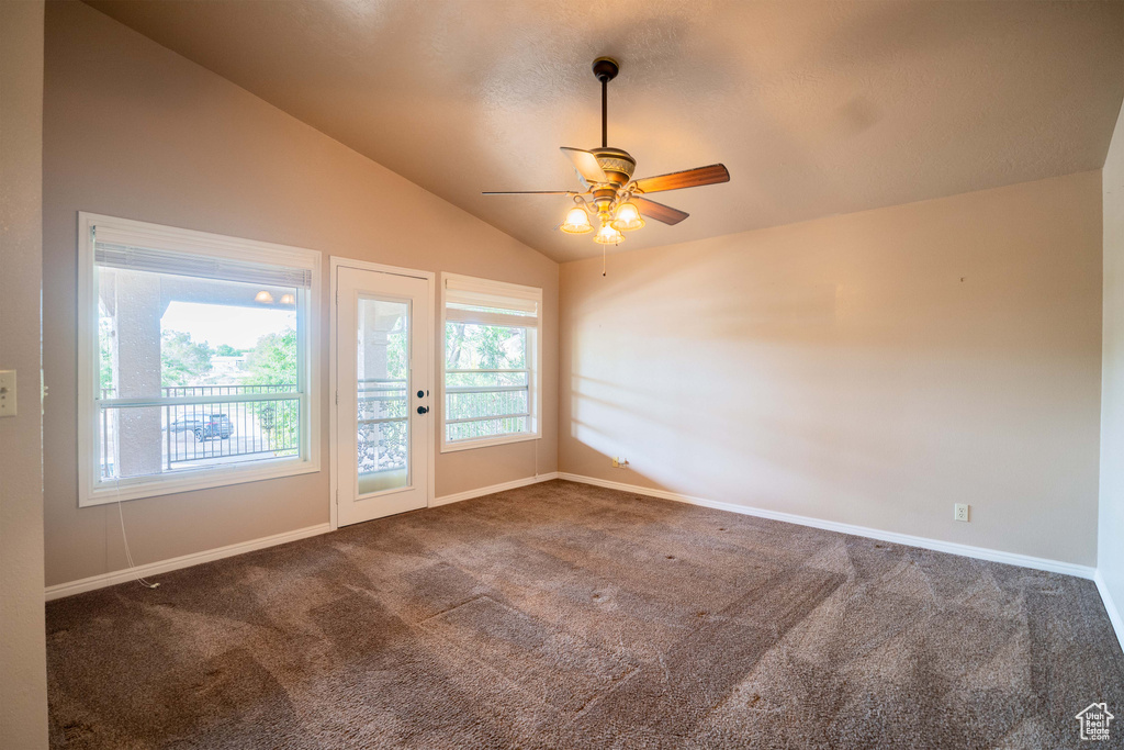 Carpeted spare room featuring lofted ceiling, ceiling fan, and baseboards