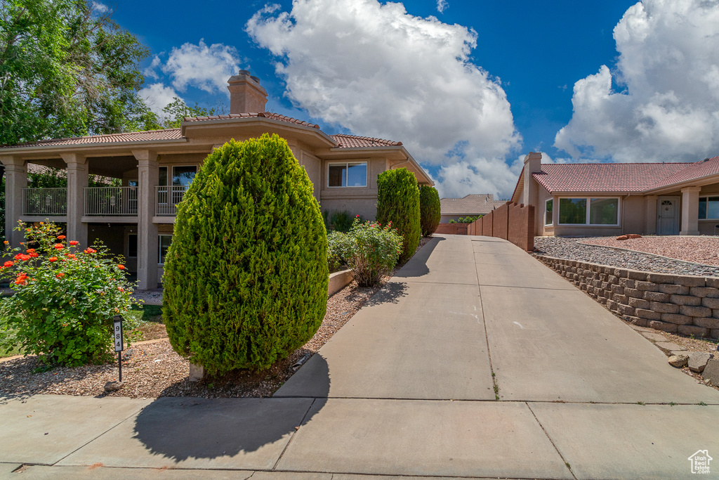 View of home's exterior with a chimney, a tile roof, stucco siding, and fence