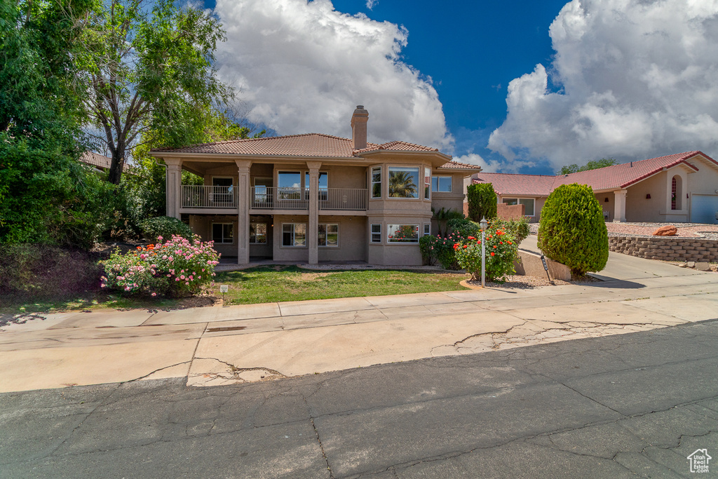 Mediterranean / spanish-style home with a balcony, a tile roof, a chimney, and stucco siding