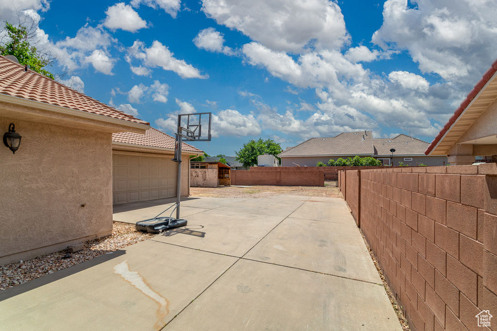 View of patio featuring driveway, a fenced backyard, an outbuilding, and a storage unit