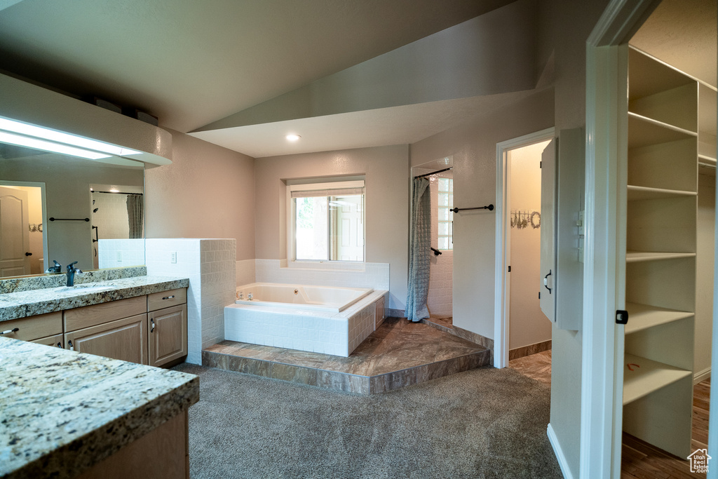 Bathroom with a shower stall, a garden tub, vanity, and vaulted ceiling