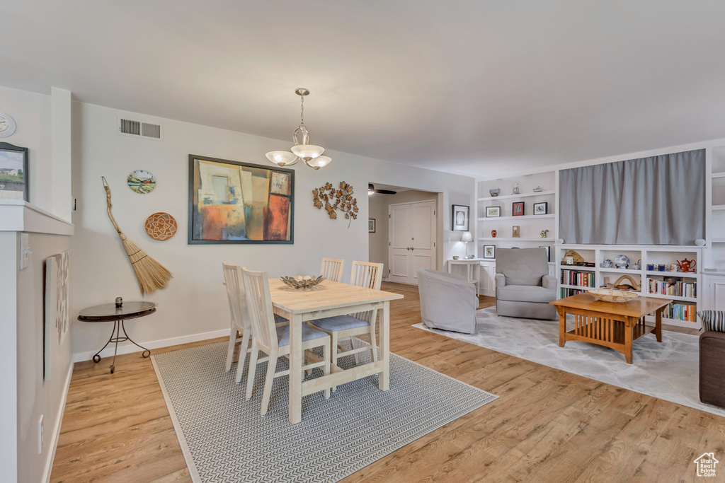 Dining space featuring light wood-style flooring, a chandelier, and baseboards