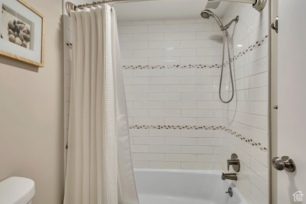 Bathroom with shower / bath combo with shower curtain and toilet