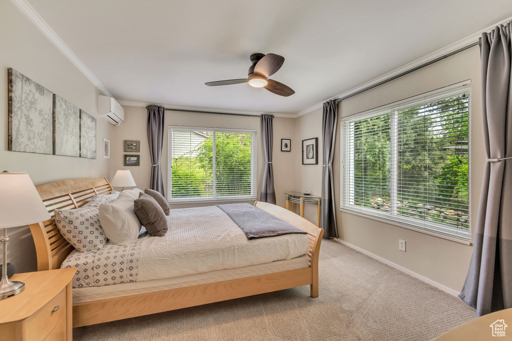 Carpeted bedroom featuring a wall unit AC, multiple windows, ornamental molding, baseboards, and a ceiling fan