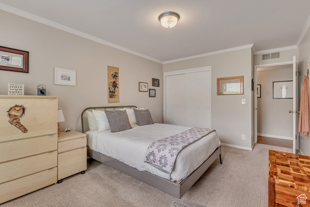 Bedroom with ornamental molding, light colored carpet, and baseboards
