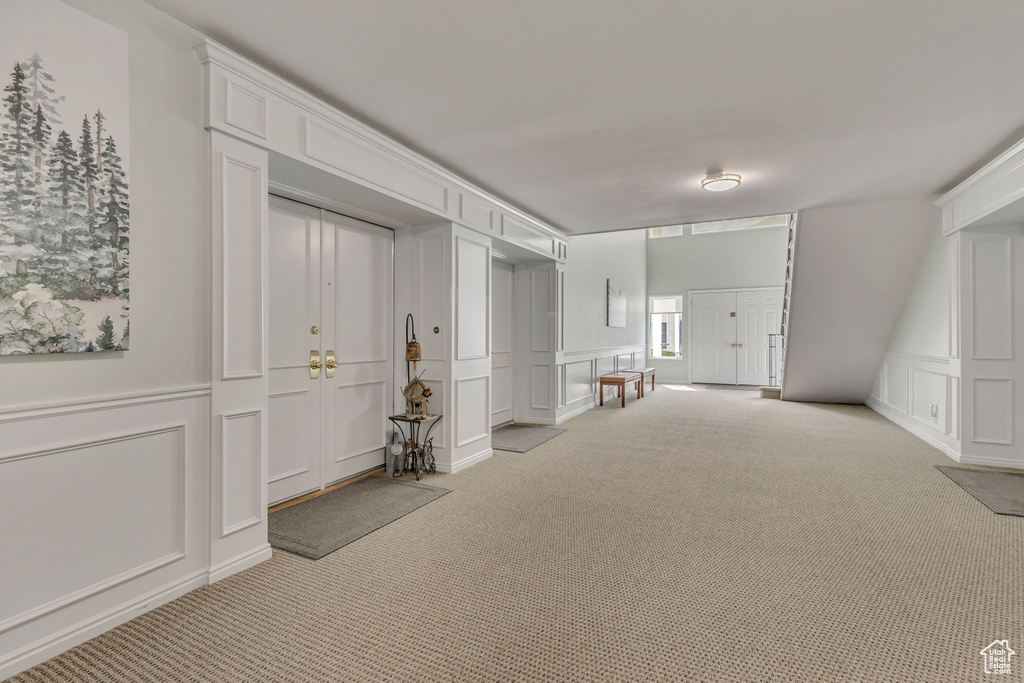 Interior space featuring a decorative wall, light carpet, and a wainscoted wall