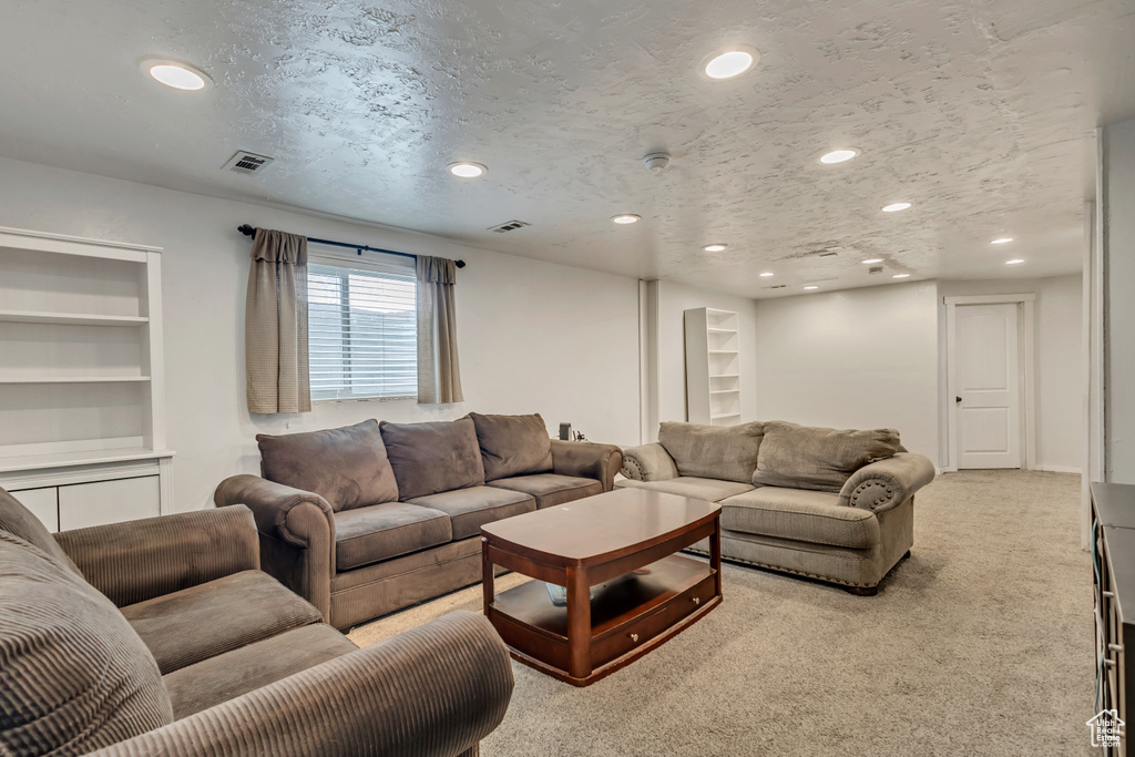 Living area with recessed lighting, light carpet, and built in shelves