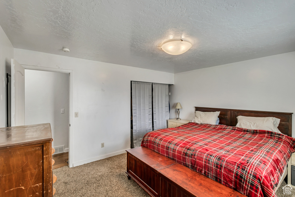 Bedroom featuring carpet, baseboards, and a textured ceiling