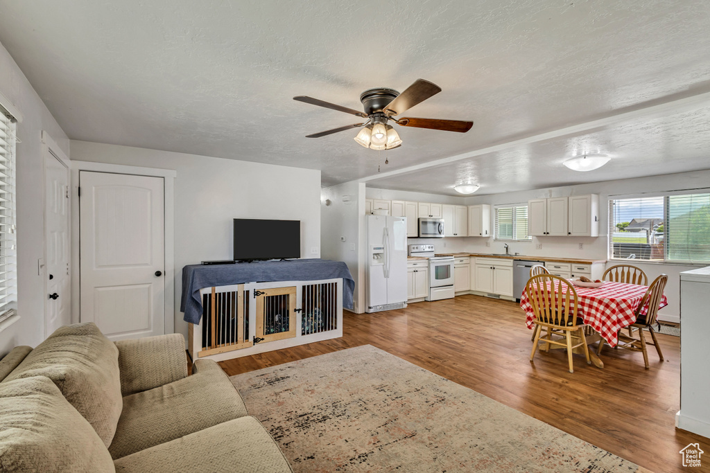 Living room with light wood-style flooring, ceiling fan, and a textured ceiling