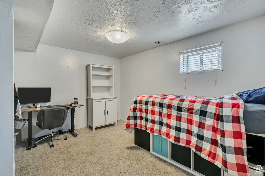 Bedroom with carpet floors, a textured ceiling, and a desk