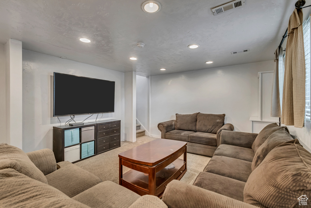 Carpeted living area with recessed lighting and stairs