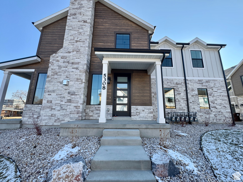 Modern home with stone siding, a chimney, and board and batten siding