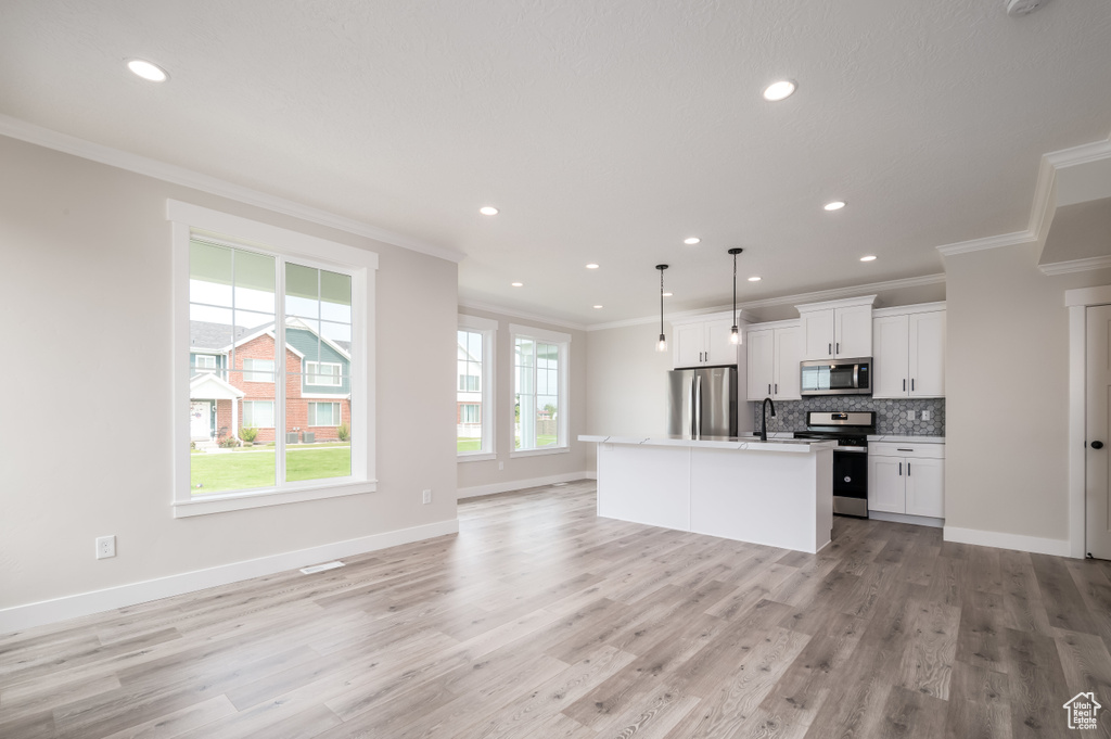 Kitchen featuring stainless steel appliances, ornamental molding, open floor plan, backsplash, and recessed lighting