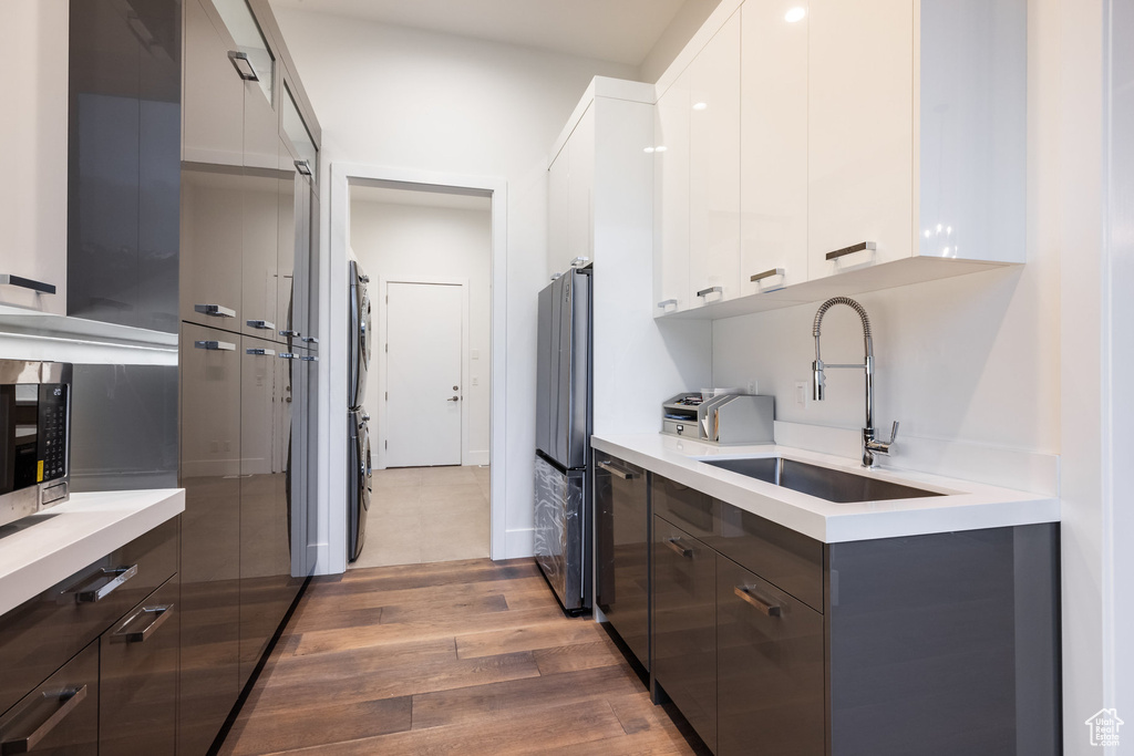 Kitchen with modern cabinets, a sink, wood finished floors, freestanding refrigerator, and light countertops