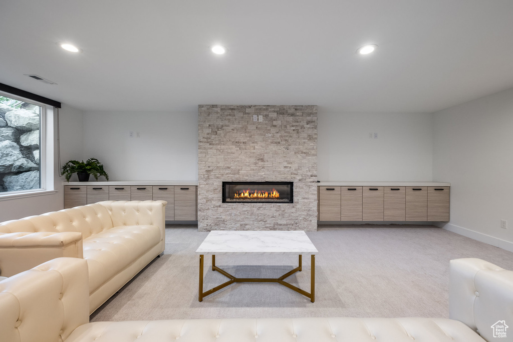 Living room featuring recessed lighting, light colored carpet, a stone fireplace, and baseboards