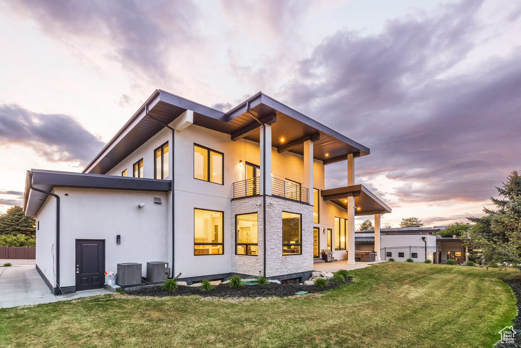 Back of property with a balcony, cooling unit, stucco siding, and a patio area