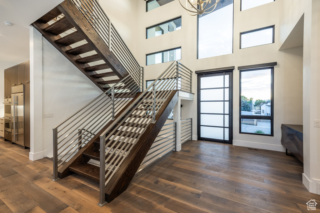 Staircase with wood finished floors, baseboards, and a high ceiling