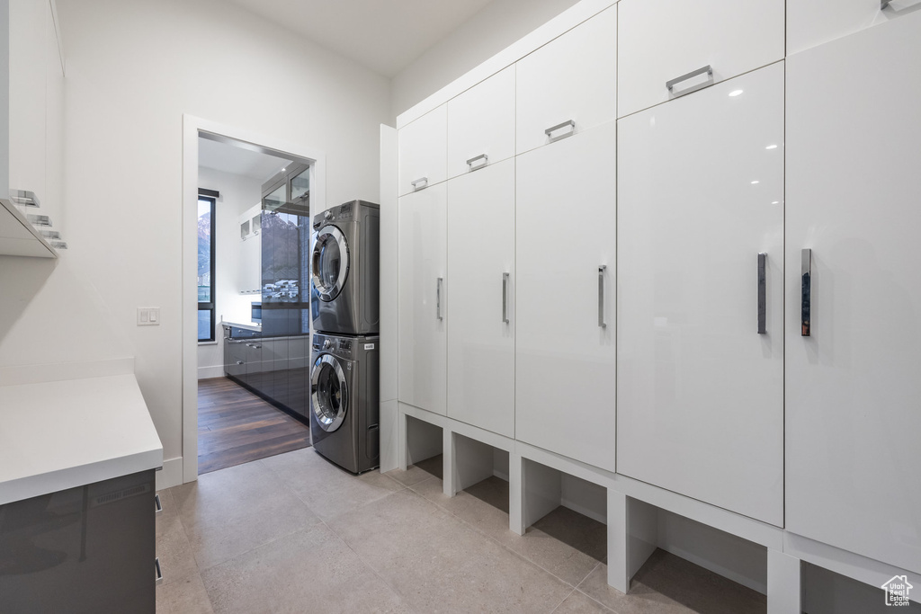 Washroom featuring stacked washing machine and dryer and cabinet space