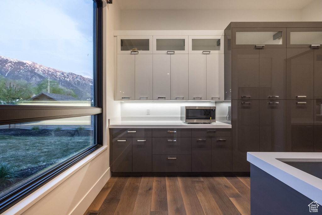 Kitchen with stainless steel microwave, glass insert cabinets, and light countertops