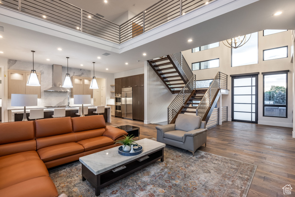 Living room featuring a high ceiling, stairway, dark wood finished floors, recessed lighting, and a chandelier