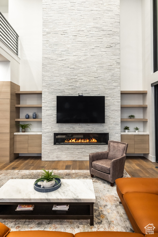 Living area with dark wood finished floors, a stone fireplace, and a high ceiling