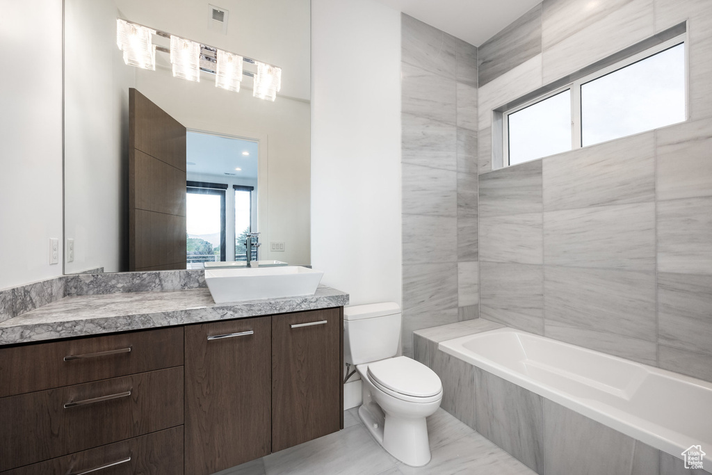 Full bath with toilet, a tub to relax in, and vanity