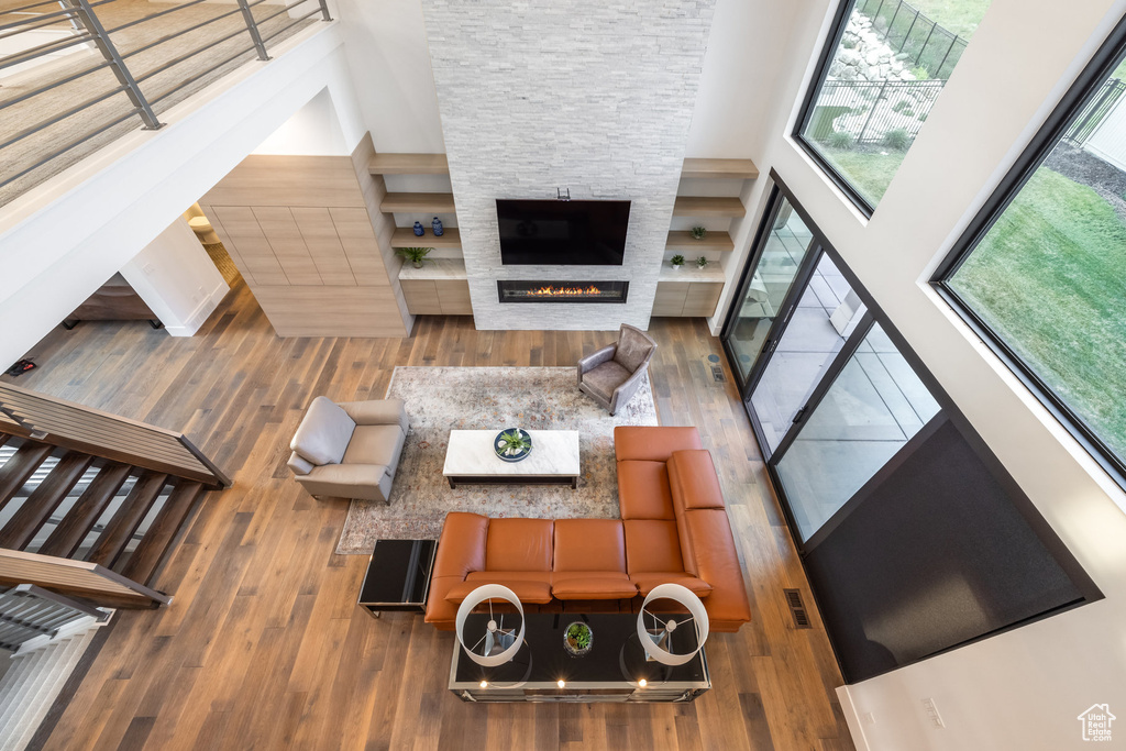 Living room with a high ceiling, hardwood / wood-style flooring, and a stone fireplace