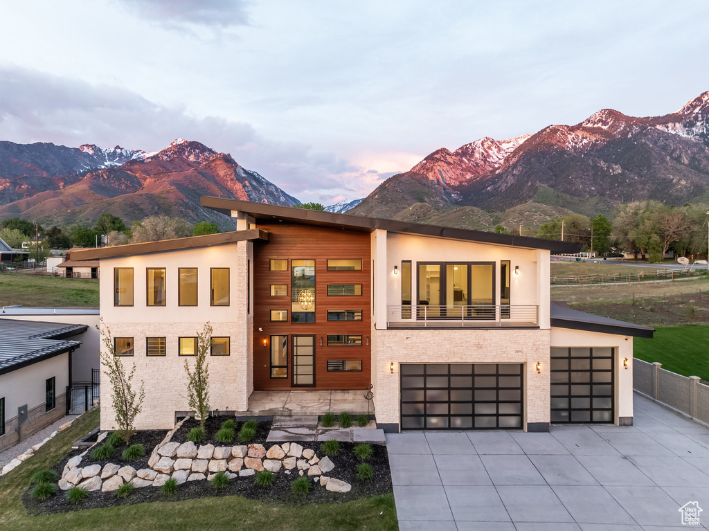 Contemporary home with a mountain view, driveway, fence, a garage, and stucco siding