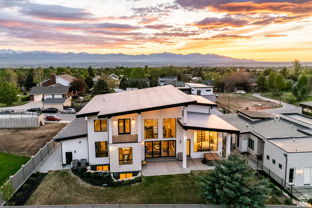 Rear view of house with a fenced backyard, a mountain view, a patio, and stucco siding