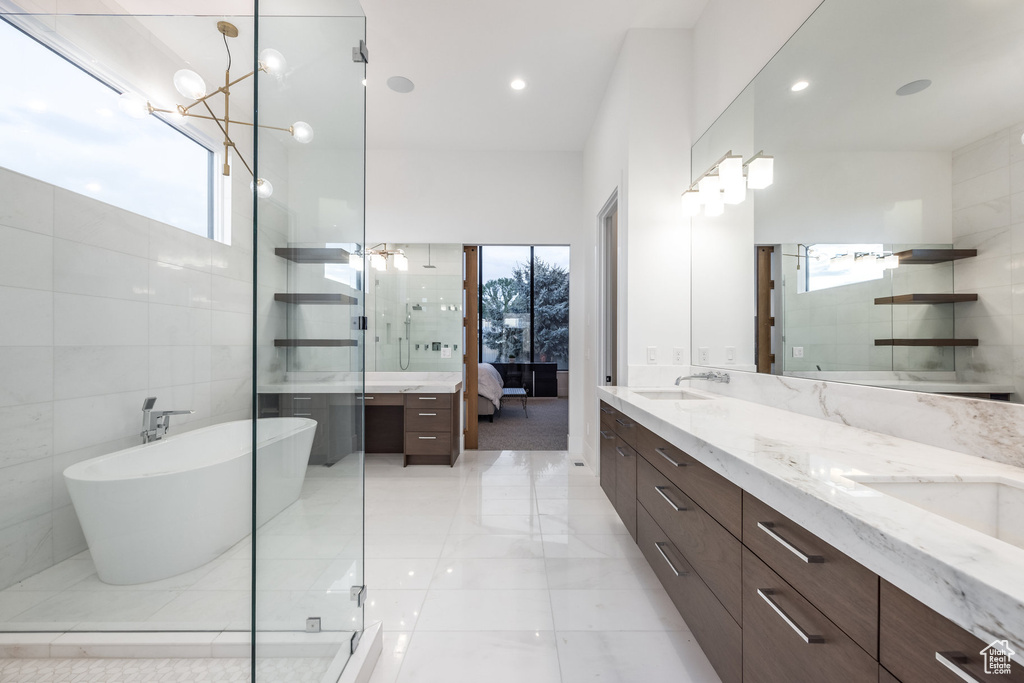 Ensuite bathroom with healthy amount of natural light, double vanity, an enclosed shower, recessed lighting, and tile walls
