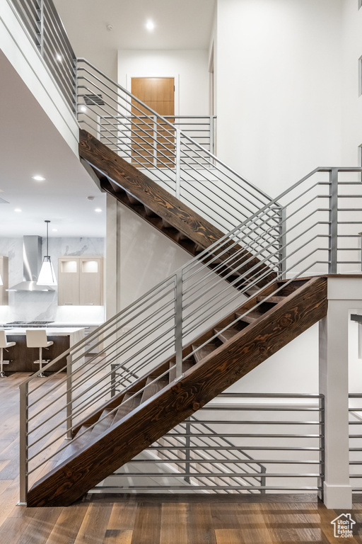 Staircase featuring wood finished floors, recessed lighting, and a high ceiling
