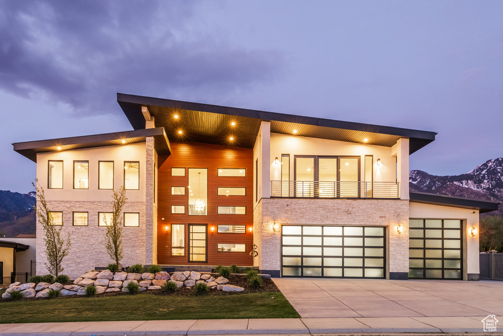 Contemporary house featuring driveway, stone siding, a mountain view, and stucco siding